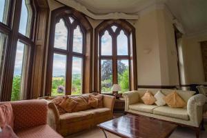 a living room with two couches and a large window at Mellington Hall Country House Hotel in Church Stoke