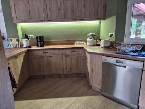 eine Küche mit Holzschränken und einem Geschirrspüler in der Unterkunft Calme et paisible maison au milieu de la foret in Arx