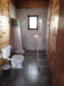 a bathroom with a toilet and a shower and a window at Las Cabañas in Las Grutas