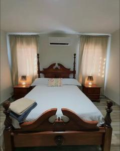 a bedroom with a large wooden bed with two lamps at Villa Lujosa en Boca Chica in Cuevas
