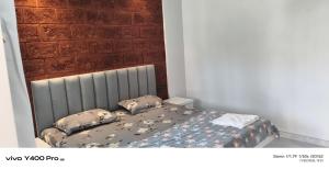 a bedroom with a bed with pillows and a brick wall at Sai Holliday's home in Alibaug