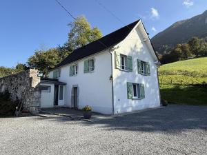a white house with green windows on a hill at Lauseig in Lourdios-Ichère
