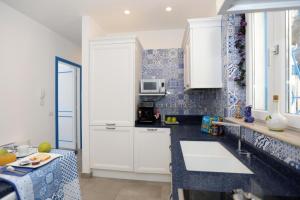 una cocina con armarios blancos y azulejos azules en Villa Dei in Positano - Camere, en Positano