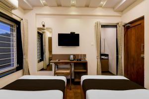 ein Zimmer mit zwei Betten, einem Schreibtisch und einem Fernseher in der Unterkunft Townhouse The 36 Inn Madhuravada Bus Stop in Rushikonda