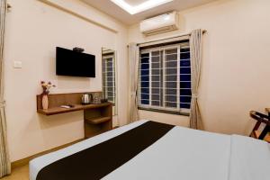 ein Schlafzimmer mit einem Bett, einem Fernseher und einem Fenster in der Unterkunft Townhouse The 36 Inn Madhuravada Bus Stop in Rushikonda