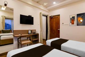 ein Hotelzimmer mit zwei Betten und einem Fernseher in der Unterkunft Townhouse The 36 Inn Madhuravada Bus Stop in Rushikonda