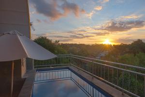 a balcony with a swimming pool and a sunset at Blue Oceana Villa in Nusa Dua