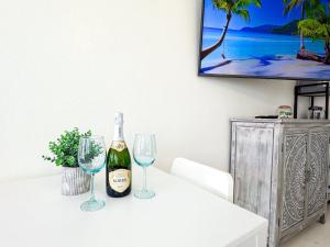 a bottle of wine and two wine glasses on a table at Exclusive Studio Steps To The Beach With Pool in Hollywood Beach