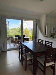 a dining room with a table and chairs and a balcony at Departamento Lago Los Molinos in Villa Ciudad de America
