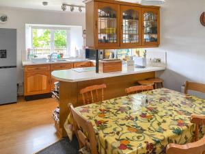 eine Küche mit einem Tisch und einem Blumentischtuch in der Unterkunft Tor Barn in Lower Boscaswell