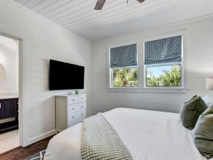 a white bedroom with a bed and a flat screen tv at Beachside Villa Unit 5 in Tybee Island