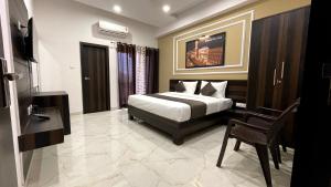 a bedroom with a bed and a chair in it at Hotel Yashoda Palace in Kota