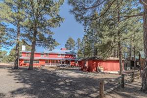 a red building with trees in front of it at Cozy Cabin in Bison Ranch in Overgaard