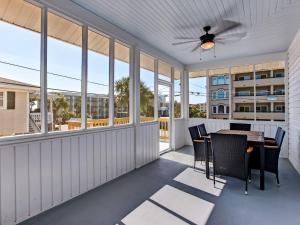 a screened porch with a table and chairs and windows at Beachside Villa Unit 3 in Tybee Island