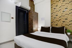 a bedroom with a large bed with black and white sheets at Hotel O Shad Residency in Patna