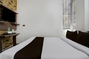 a white and black bed in a room with a window at Hotel O Shad Residency in Patna