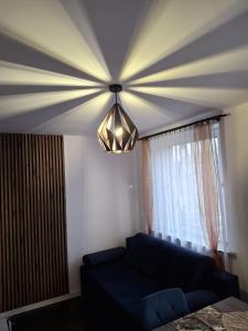 ein Wohnzimmer mit einem blauen Sofa und einem Kronleuchter in der Unterkunft Apartament pod Czarną Górą in Stronie Śląskie + 9 Fotos