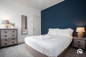 une chambre avec un grand lit blanc et un mur bleu dans l'établissement The Ryton Free Wi-fi Parking, à Winlaton