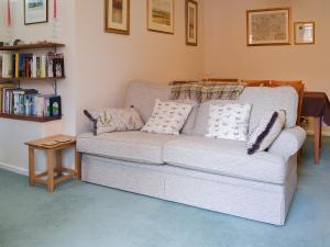 eine weiße Couch mit Kissen in einem Wohnzimmer in der Unterkunft Trentham Cottage in Snettisham