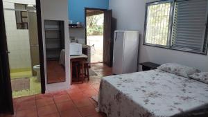 a bedroom with a bed and a bathroom with a refrigerator at Casa a 130 metros da praia de Boiçucanga in São Sebastião