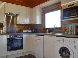 a kitchen with white cabinets and a sink and a washer at Cider Mill Lodge - Hw7420 in Tintern