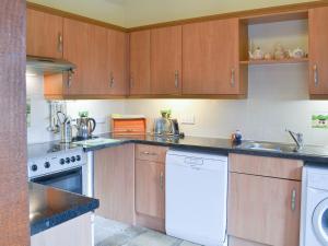 a kitchen with wooden cabinets and a white dishwasher at Hog Pits - 18961 in Tytherton Lucas