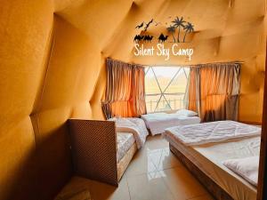 two beds in a room with a sign that reads silent six camp at SILENT SKY lUXURY CAMP in Wadi Rum