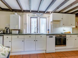 a kitchen with white cabinets and a window at The Tack Room - Uk30438 in Kingsbury Episcopi
