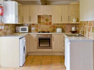 Una cocina con electrodomésticos blancos y gabinetes de madera. en Sorrel - E4321, en Ludham 7 fotos más
