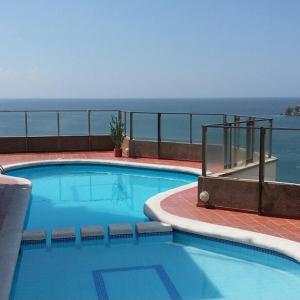 ein großer Swimmingpool mit dem Meer im Hintergrund in der Unterkunft Apartamento en el Rodadero in Santa Marta