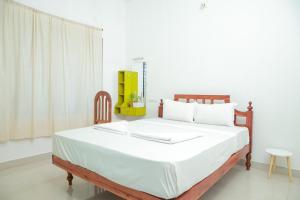 a bedroom with a large bed with white sheets at Lakshmi Ayurveda & Yoga Apartment in Kovalam