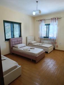 three beds in a room with windows at Northern Lane in Shkodër