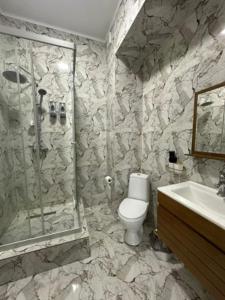 a bathroom with a shower and a toilet and a sink at Shahristan Hotel in Aktau
