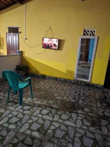 una pared amarilla con una silla y un televisor en la pared en Pousada Marudá, en Marapanim