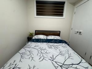 Dormitorio pequeño con cama con edredón blanco y negro en 1BHK, Close to Whyte ave, Downtown, UOFA 10633, en Edmonton
