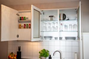 a kitchen with white cabinets with dishes in it at Modernes Apartment - Basel, Kur & Golf in Bad Bellingen +27 photos