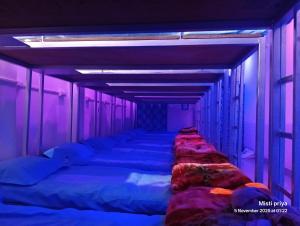 a row of beds in a room with purple lights at Ac Comfort guest house in Deoghar