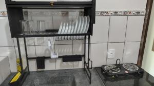 een keuken met een plank met borden en keukengerei bij Espaço Acalanto in Rio das Ostras