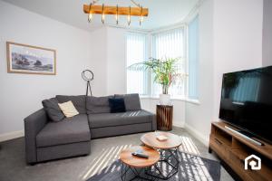 a living room with a couch and a tv at Stylish Cosy Two Bed Apartment - Coast Location in Whitley Bay