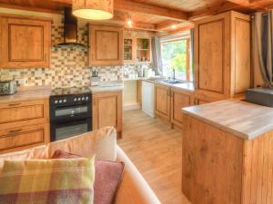 a kitchen with wooden cabinets and a stove top oven at Hadrians Garden Villa in Bardon Mill