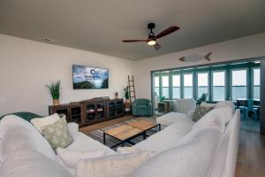 a living room with white couches and a ceiling fan at Sulla Sabbia in Edisto Island