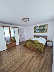 a bedroom with a bed and a wooden floor at Luci's House in Jucu de Mijloc
