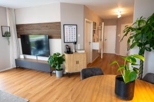 a living room with a television and a table with plants at Modernes Apartment - Basel, Kur & Golf in Bad Bellingen