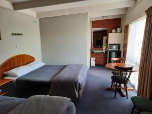 a hotel room with a bed and a table and a kitchen at Abbotswood Motor Inn in Geelong
