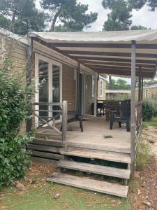 eine hölzerne Veranda mit Markise und einem Picknicktisch in der Unterkunft Mobil home 6 pers camping 5 in Montalivet-les-Bains