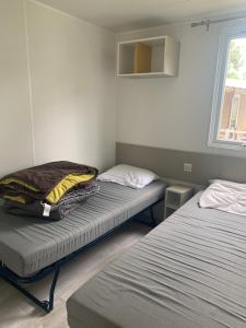 ein Schlafzimmer mit zwei Betten und einem Fenster in der Unterkunft Mobil home 6 pers camping 5 in Montalivet-les-Bains