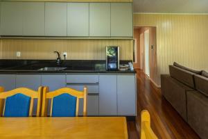 ベント・ゴンサルベスにあるRecanto dos Vinhedosの白いキャビネットとテーブルと椅子のあるキッチン