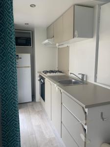 eine Küche mit weißen Schränken, einer Spüle und einem Kühlschrank in der Unterkunft Mobil home 6 pers camping 5 in Montalivet-les-Bains