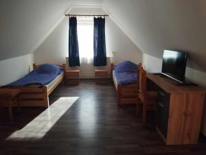 a attic room with two beds and a television at NADENKA & MGR Vendégház in Alsótelekes