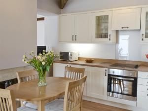 a kitchen with a wooden table with a vase of flowers on it at The Coach House in Whittingham